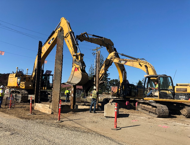 Excavators working in tandem to construct 20+ feet deep sewer line for the Cox Creek project